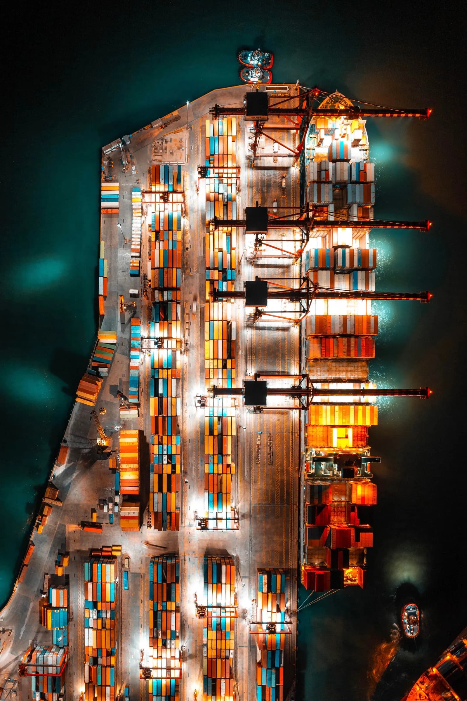 Container ship being unloaded at night, seen from above