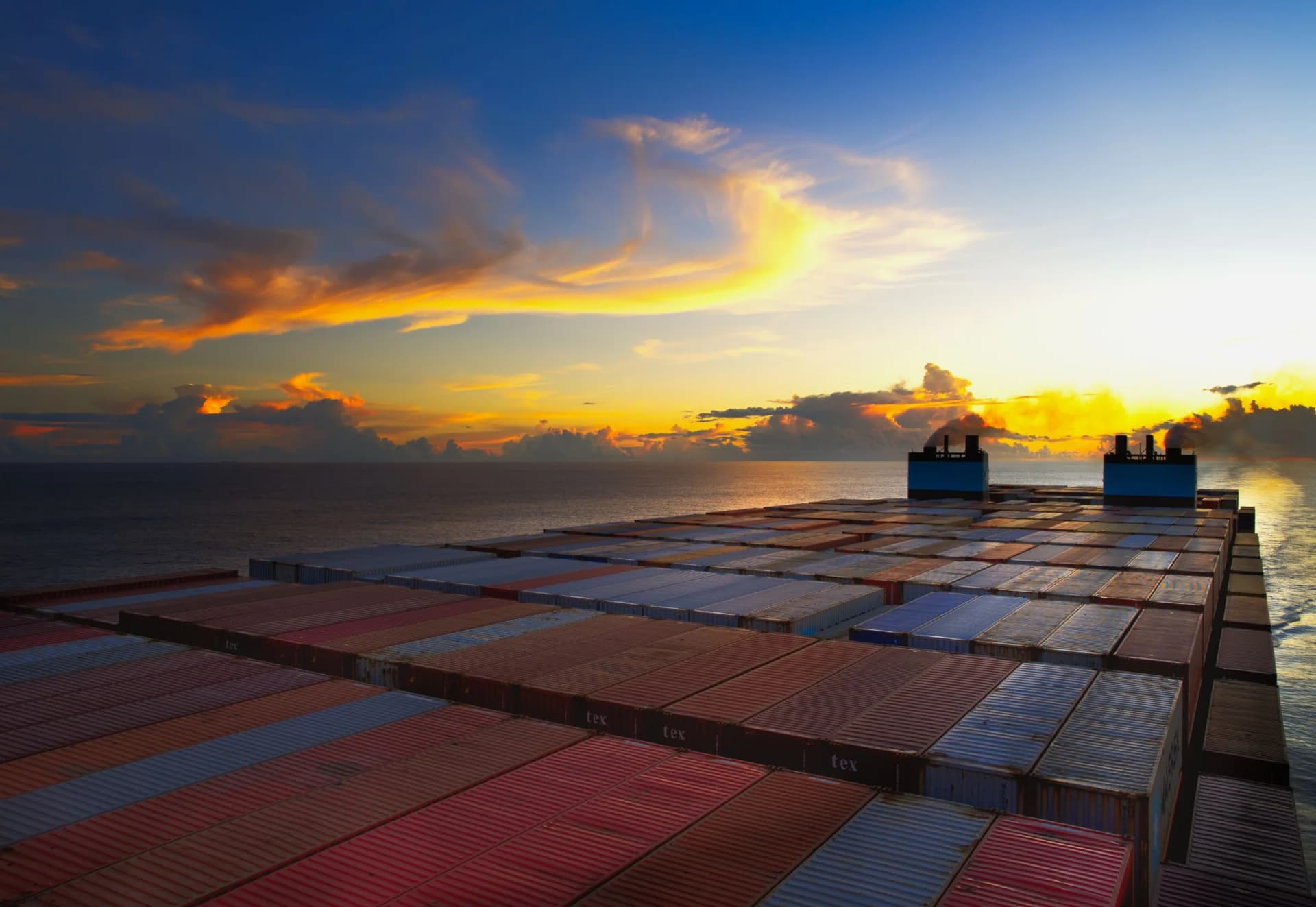 Containers stacked on a vessel deck at sunset